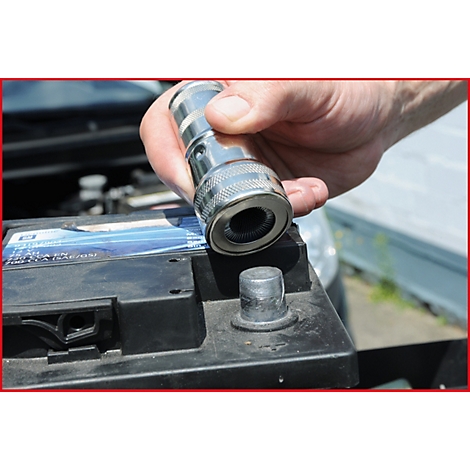 Person hält eine Batteriepolbürste über der Batterie, bereit zur Reinigung.